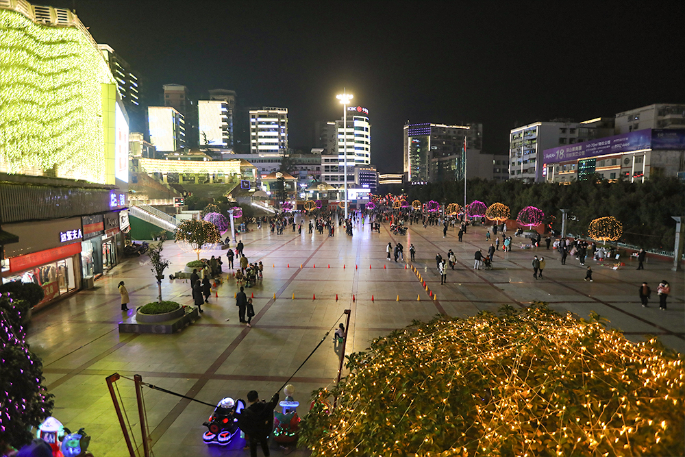 夜晚城市廣場，燈火璀璨，人流如織